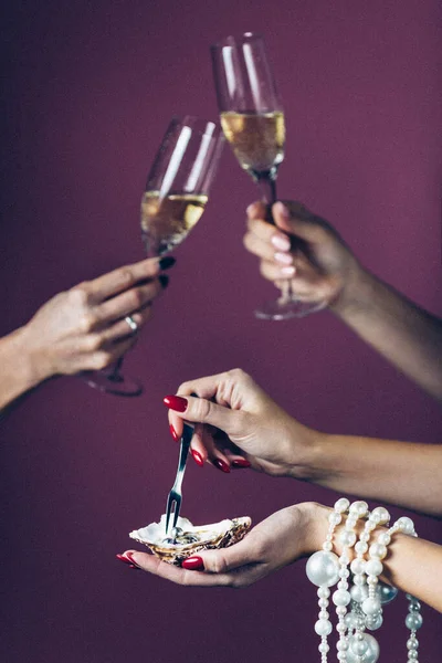 Copos de taças de champanhe clink no fundo, uma mão feminina segura uma casca de ostra com pérolas de jóias. Fura a saliva. Cartaz do conceito — Fotografia de Stock