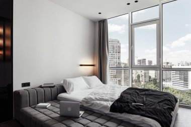 Parlak modern iç mekan, siyah beyaz tonlarda yatak odası. Kanepesi, bilgisayarı ve panoramik pencereli bir odada kitapları olan rahat bir oda. beyaz sayfalar