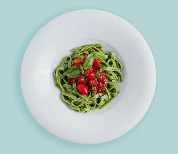 Ev yapımı ıspanak soslu spagetti, yeşil spagetti, kızarmış domates ve taze fesleğen yaprağı, beyaz arka planda vejetaryen yemekleri. Çak. Yukarıdan görünüm