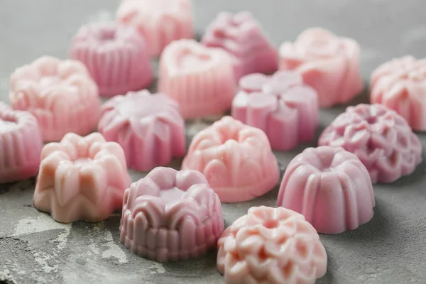 The small handmade soap is laid out in the form of a square in even rows on a concrete background. Lots of pink soap. Close-up — Stock Photo, Image
