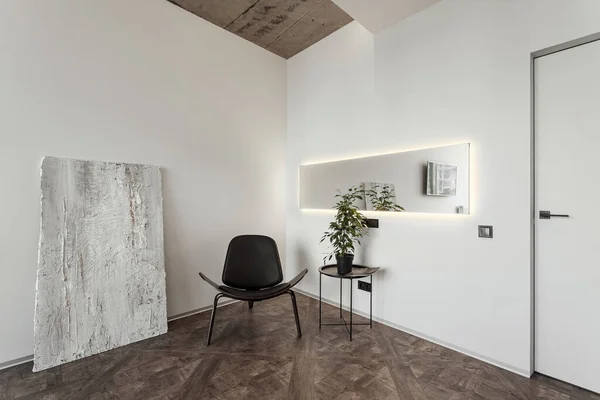 La esquina de la habitación con paredes blancas donde se puede ver la silla, el espejo y el piso elegante con una planta de habitación. fragmento de muro de hormigón — Foto de Stock