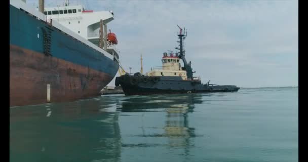 Camera movement along the waterway, ship view. Tugboat and side of the big ship — Stock Video