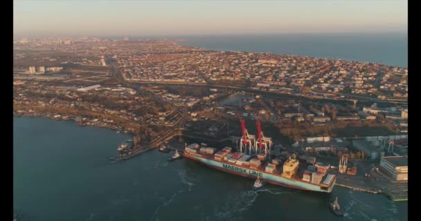 19.04.2020. Black Sea. Panoramic view of the harbour with the seaport. Tugboats have moored a cargo ship to shore. View from above at sunset — Stock Video