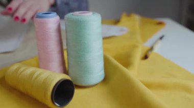Moda tasarımcısı, genç bir kadının elleri, bir kalıp yaratır ve bir üniforma boyar, bir stüdyoda çalışır, şık kıyafetler yaratır. Teçhizatı ve araçları arka planda görünür konforlu atölye.