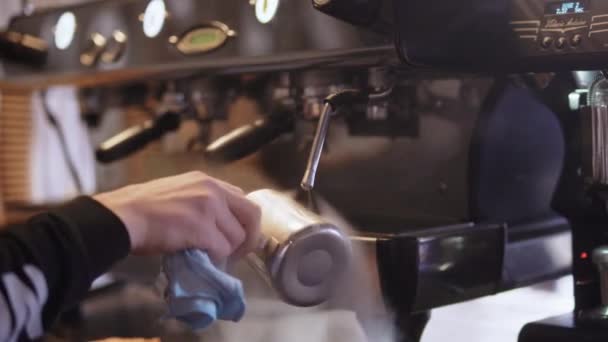 Kahve makinesinin yanında kahve yaptıktan sonra barista metal sütçüyü siler. — Stok video