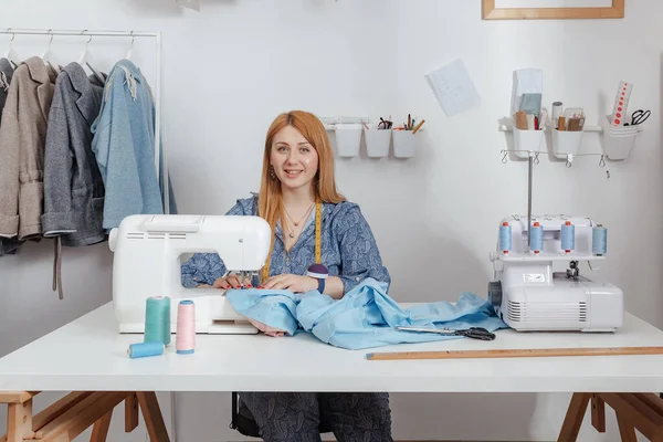 Terzi dikiş makinesi üzerinde çalışırken atölyesinde gülümsüyor. Moda Tasarımcısı