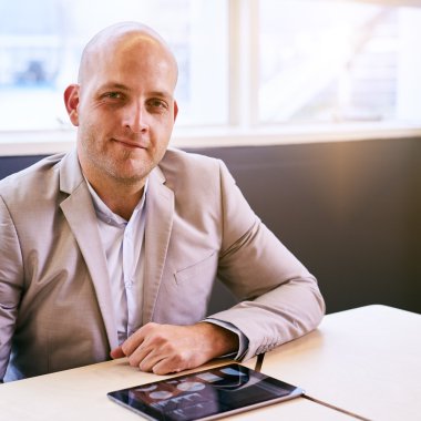 Önünde tablet olan kameraya bakan adam