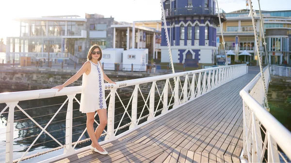 Красивая женщина в солнечных очках смотрит на камеру, стоящую на мосту — стоковое фото