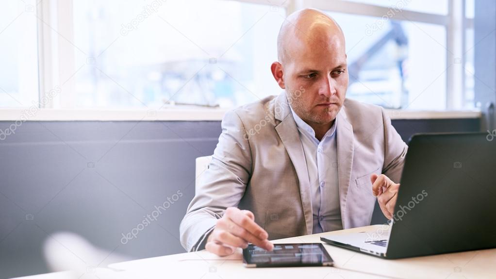 Professional business man working on his portable tablet and computer