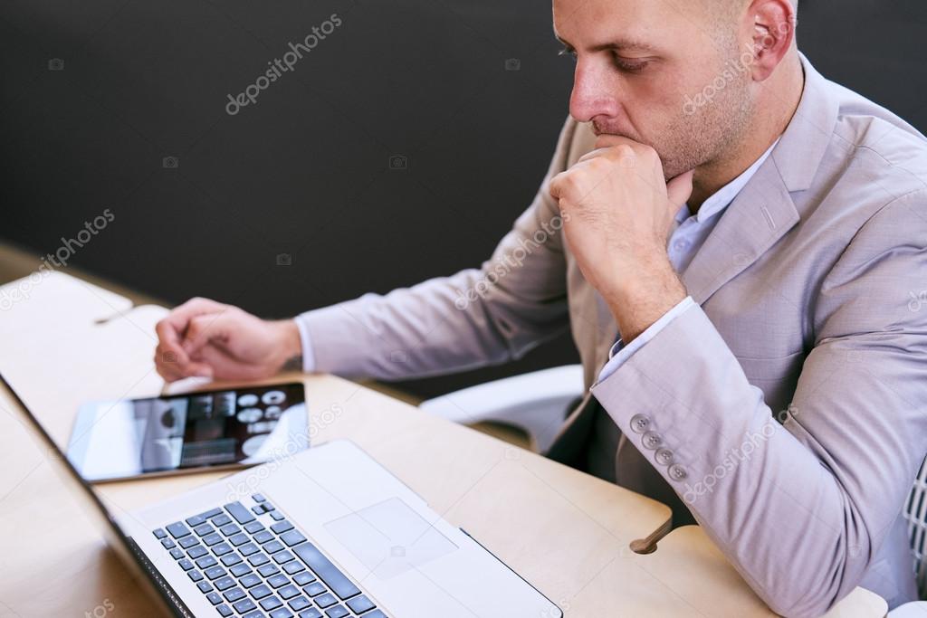 Professional business man working on his portable tablet and computer