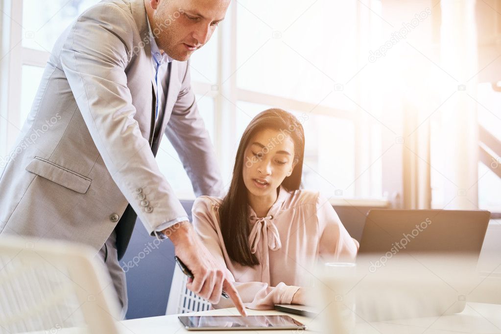 Businessman pointing at tablet with female colleague paying attention