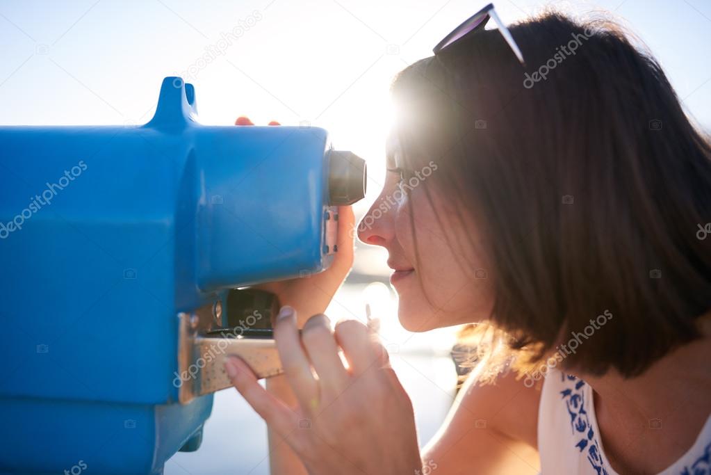 woman looking through a blue iron telescope