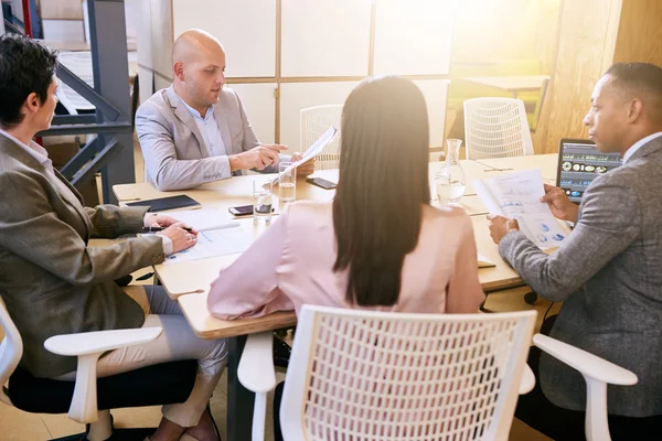 Business meeting between four professional entrepreneurial executives indoors — ストック写真