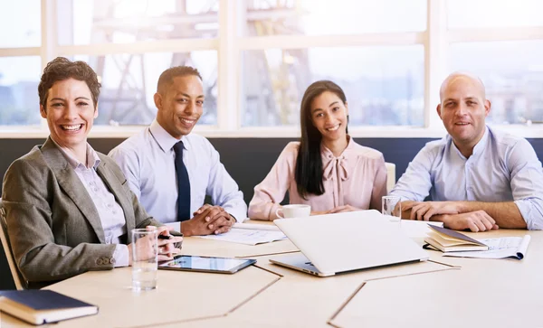 Cuatro profesionales de negocios mirando a la cámara durante una reunión — Foto de Stock