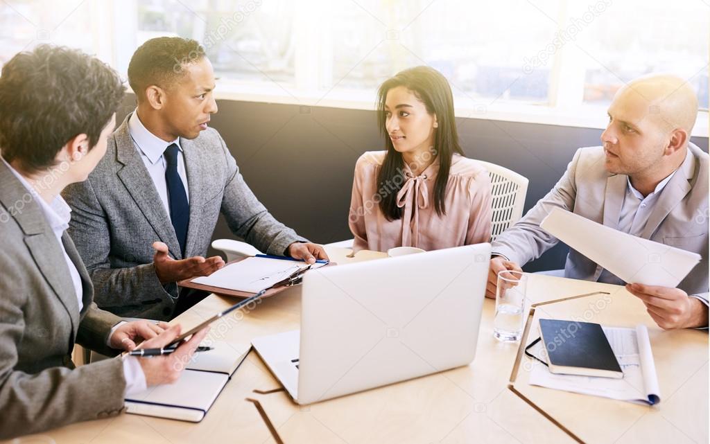 Business meeting between four professional executives in conference room