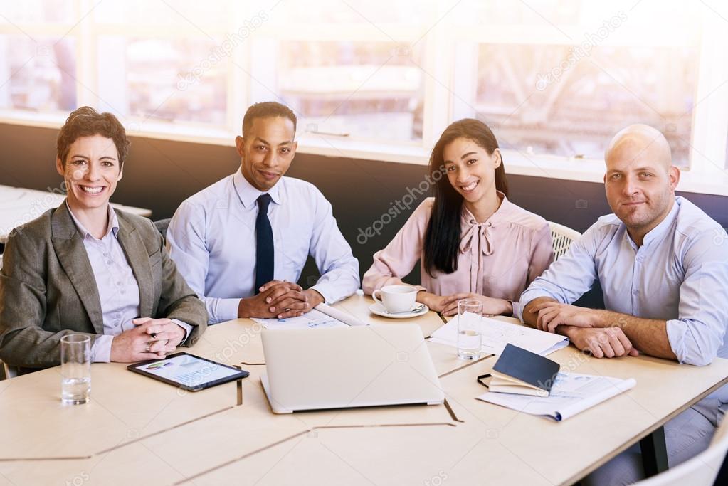 four business professionals looking at the camera during a meeting