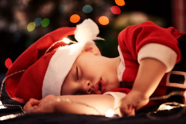 Baby sleeping in santa outfit for christmas season near tree — Stock Photo, Image