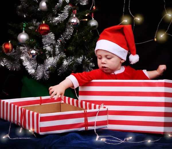 Baby in santa outfit sitting inside a wrapped gift box — Stock Photo, Image