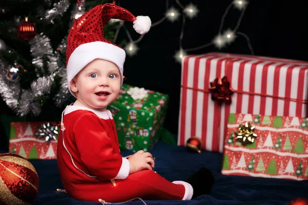Baby sitting with gifts under christmas tree — Stock Photo, Image