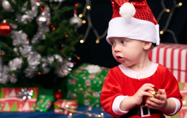 Santa baby looking at copyspace with christmas tree and decorations — Stock Photo, Image