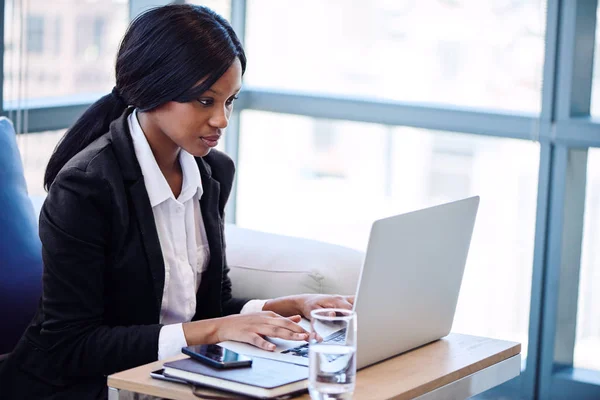 Zwarte zakenvrouw bezig met haar laptop in een business lounge — Stockfoto