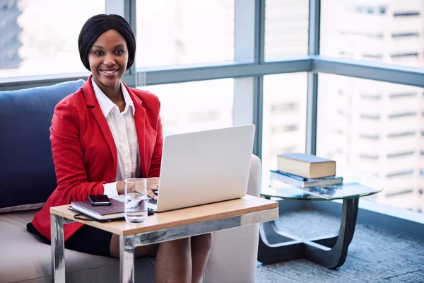 Black businesswoman smiling at the camera while seated on sofa — Stock Photo, Image