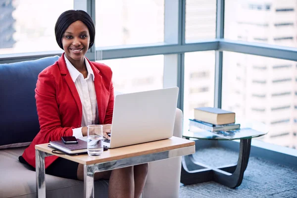 Negro mujer de negocios sonriendo a la cámara mientras está sentado en el sofá — Foto de Stock