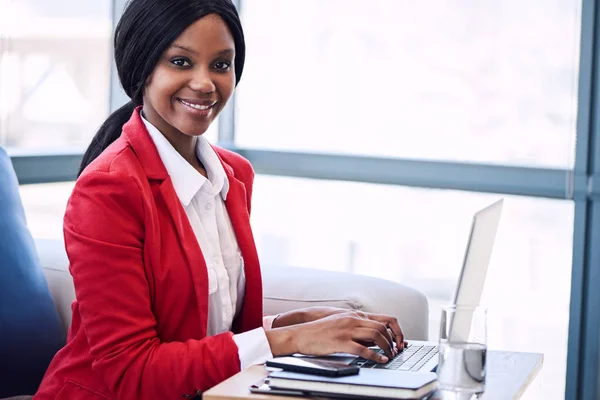 Black businesswoman looking into camera with her hands on laptop — Stock Photo, Image