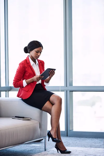 Молодая африканская бизнесвумен смотрит на экран на своем планшете — стоковое фото