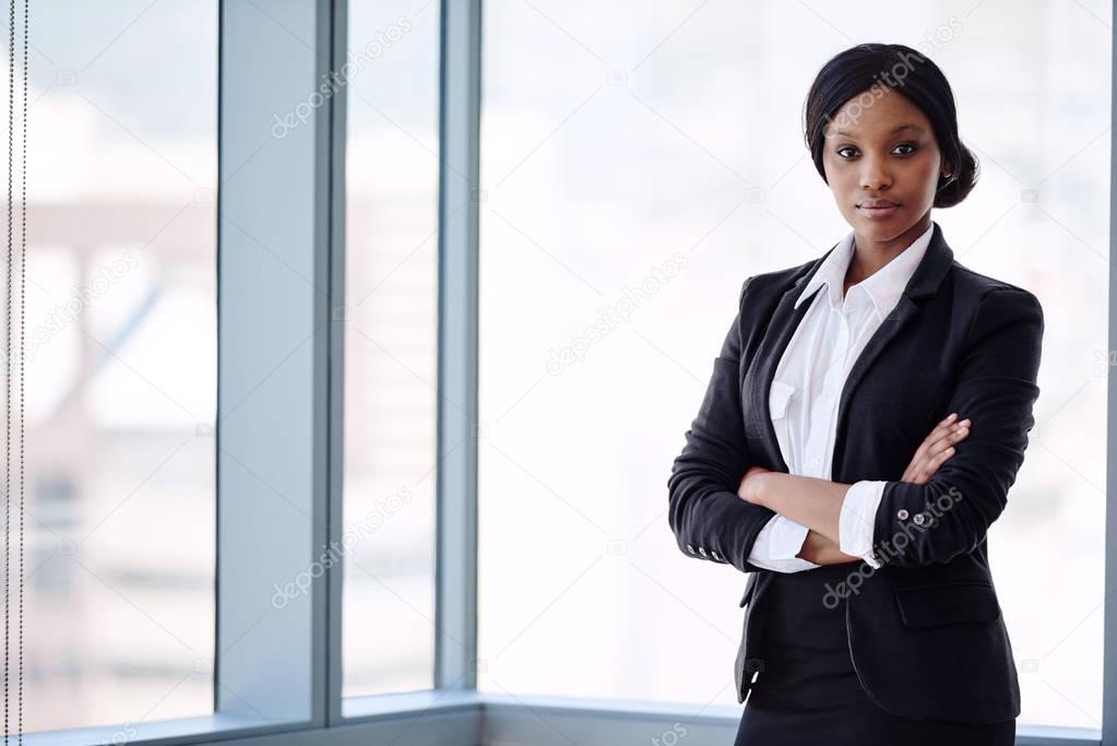 Formally dressed blackbusiness woman looking at camera with arms crossed