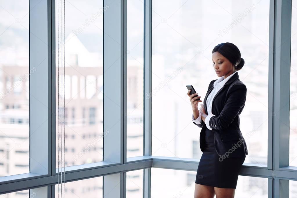 Mature black business woman texting while standing