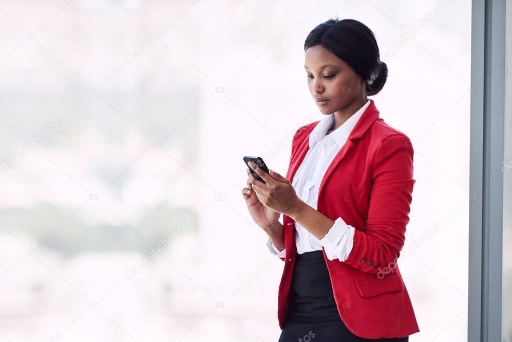 Young formally dressed african american woman busy using her phone