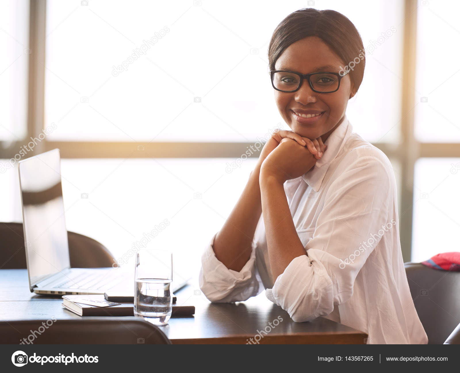 Successful black woman smiling at camera while sitting at ...