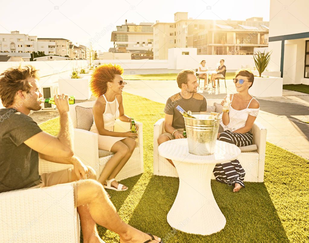 Friends enjoying each others company in the sun with drinks