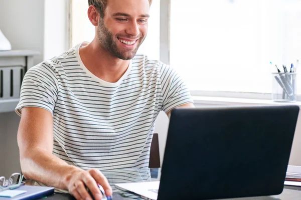 Jovem estudante do sexo masculino feliz sorrindo enquanto sentado atrás de seu laptop — Fotografia de Stock