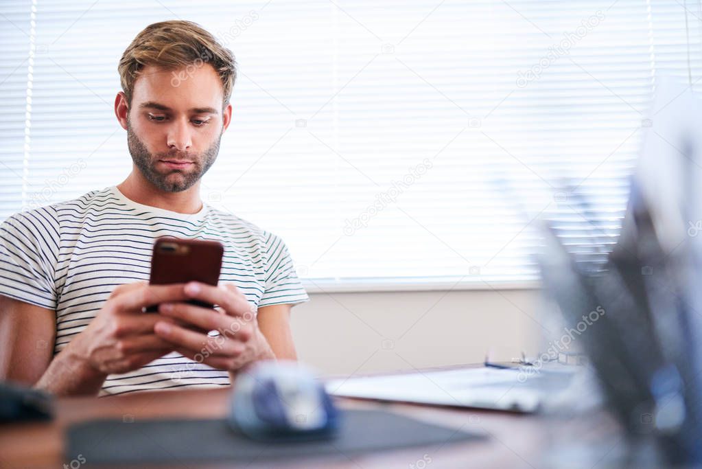 Adult caucasian man busy typing on his phone while seated