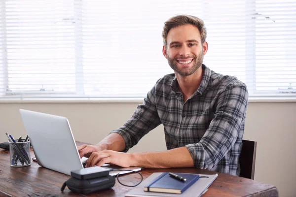 Ung manlig student som ler mot kameran medan du arbetar på uppdrag — Stockfoto