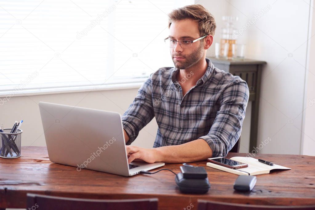 Modern man typing on a laptop while seated at desk