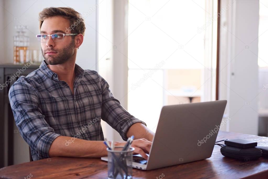 Successful businessman looking over his shouler out window at office