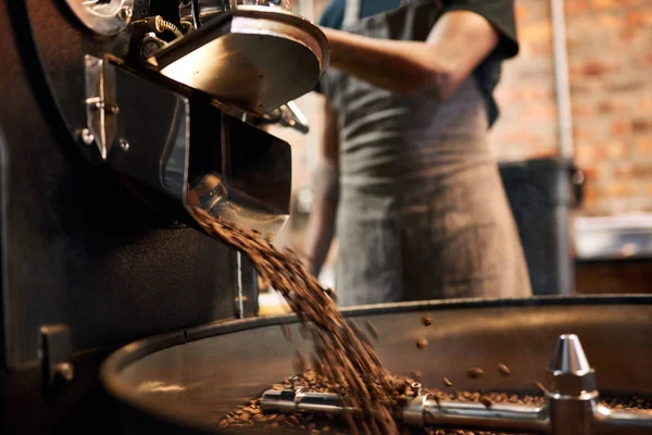 Granos de café que se vierten de una máquina de tostado de café — Foto de Stock