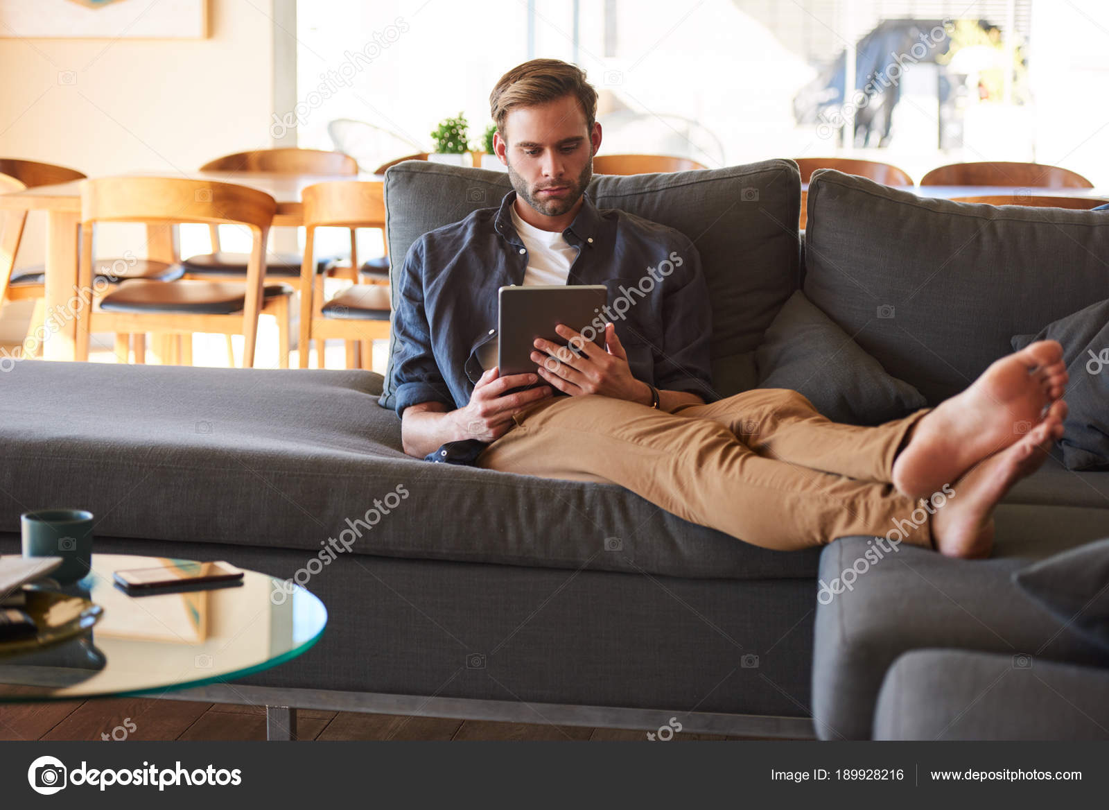 Handsome man feet Handsome man sitting with feet on couch holding