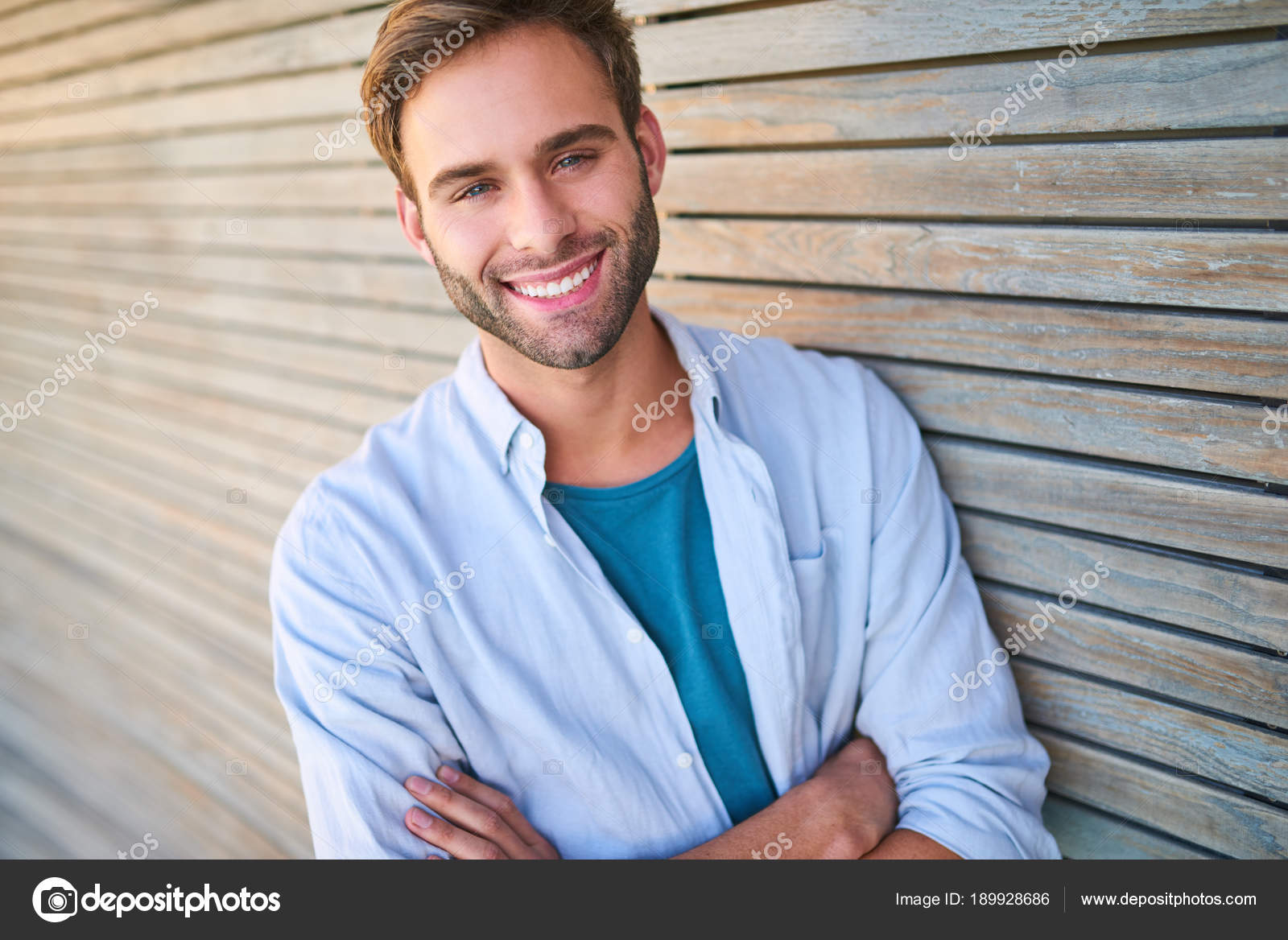 Attractive white guy smiling at camera leaning against wooden cladding