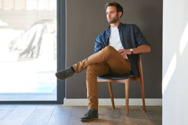 Modern ahşap sandalye evde oturan yakışıklı beyaz adam