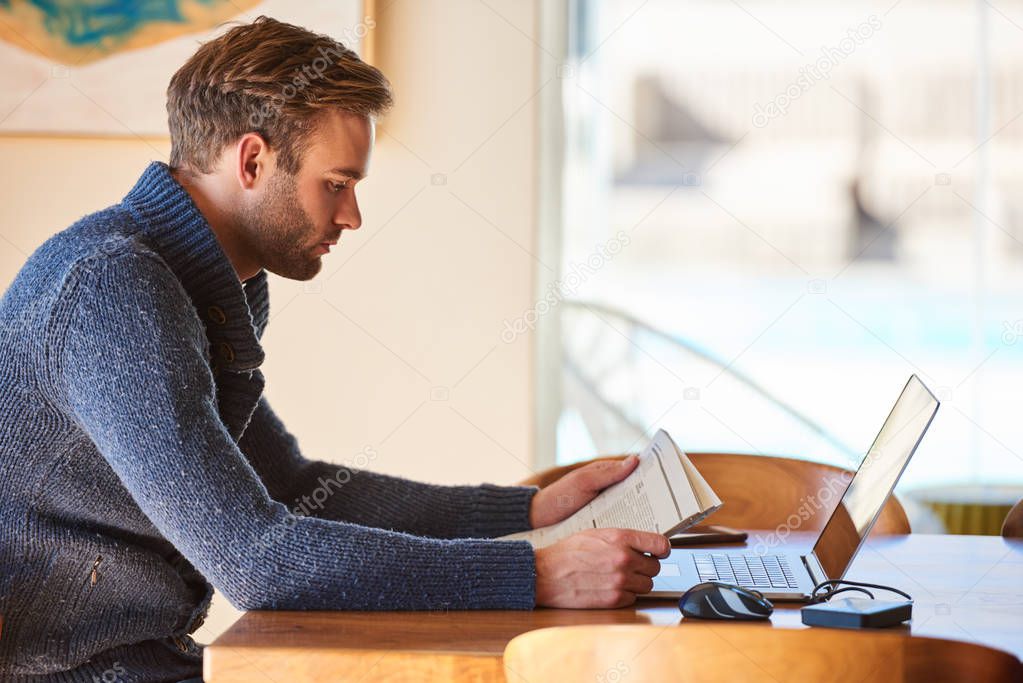 Handsome caucasian man busy reading a newspaper at home