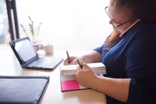 Business woman busy multitasking while seated at her desk — Stock Photo, Image