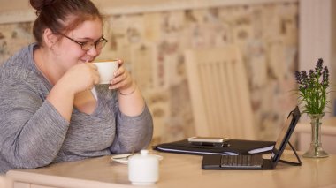 Orta derecede obez işkadını kahve tutarken bir kafede oturuyor
