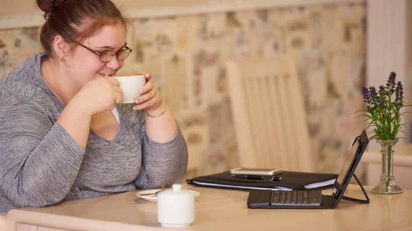 Moderately obese businesswoman sitting in a cafe while holding coffee — Stock Photo, Image