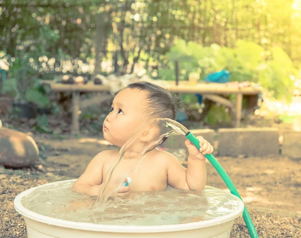 Baby bathing out door , baby hand holding the hose which water f — Stock Photo, Image