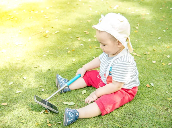 Asian baby taking selfie photo on the green grass field in the park — Stock fotografie