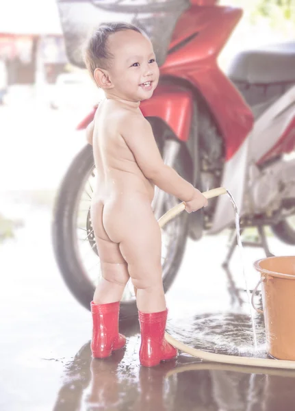Asian baby boy use hand holding water hose to washing motorcycle — ストック写真